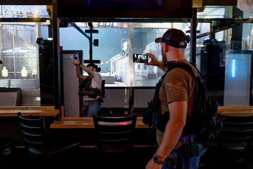 A person taking a photo with a smartphone, wearing a cap and a backpack. 2