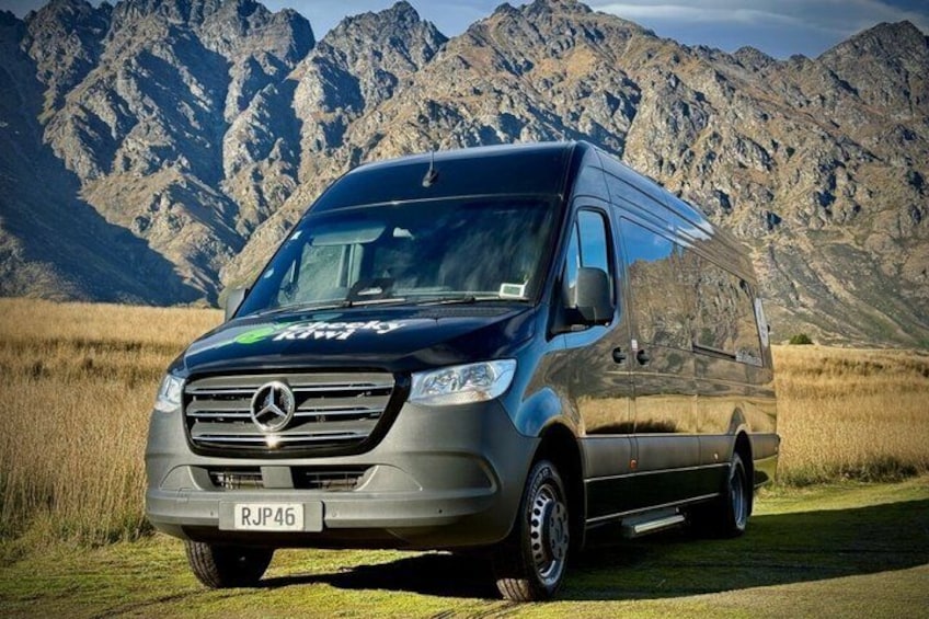 A Mercedes-Benz Sprinter van parked in a field with mountains in the background. 3