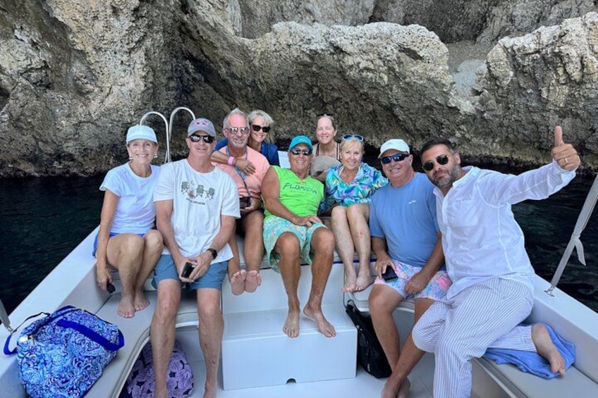 A group of people on a boat with rocky cliffs in the background. 3