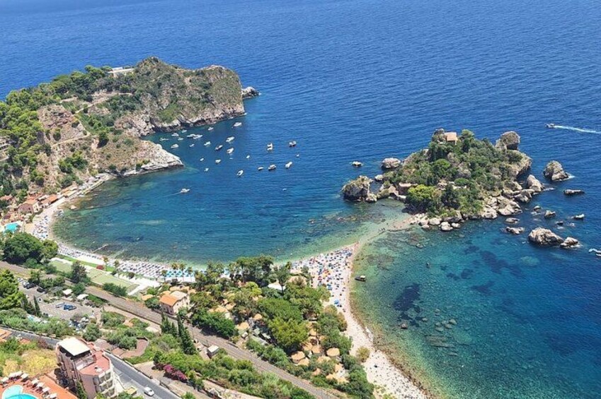 A coastal landscape with clear blue waters, rocky islands, and a beach area. 4