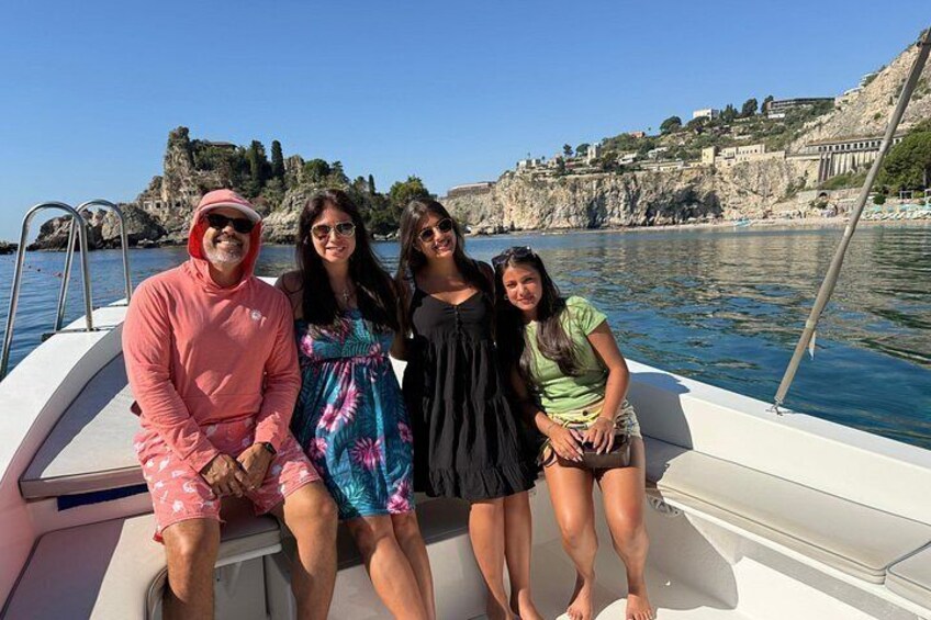 A group of people on a boat with a rocky coastline and buildings in the background. 2