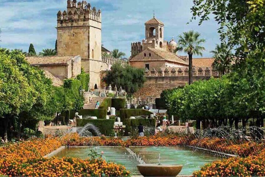 A historic castle with a tower, surrounded by a garden with orange flowers and a fountain. 4