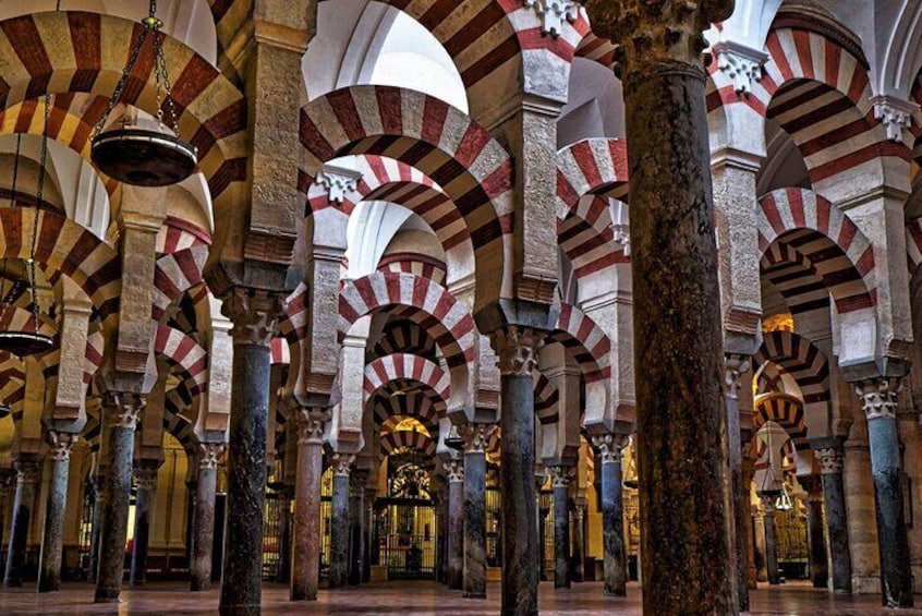 A mosque interior with red and white striped arches and columns. 1