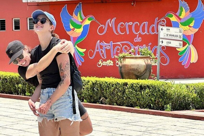 Two people embracing in front of a mural with a bird and text. 5