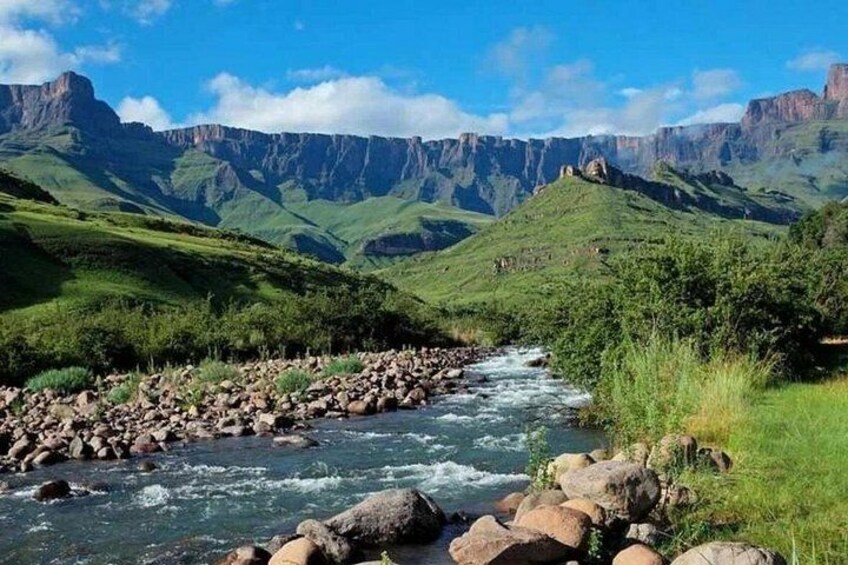 A river flowing through a valley with green hills and rocky terrain. 4
