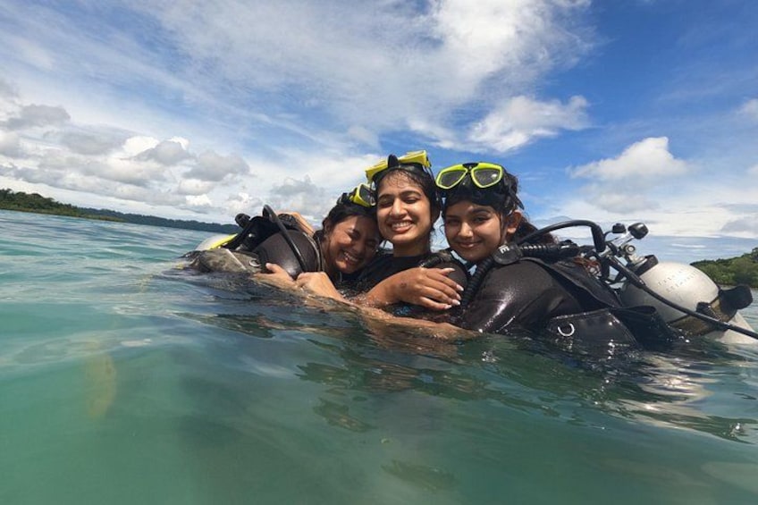 Three people in a body of water with a clear sky and distant land. 4