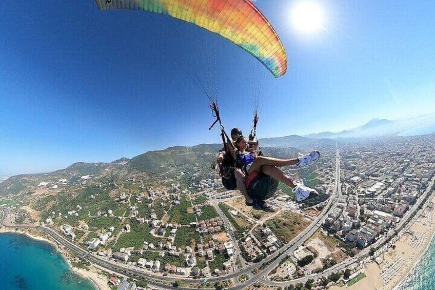 Una persona practica parapente sobre una ciudad costera, con calles y edificios a la vista. 2