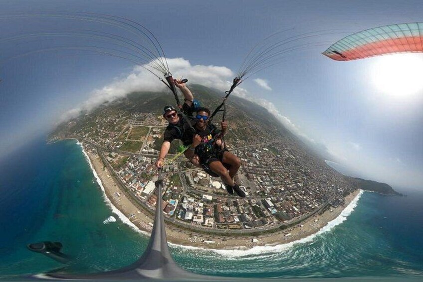 Una persona fa parapendio sopra una città costiera, con vista sull'oceano e una spiaggia sottostante. 2
