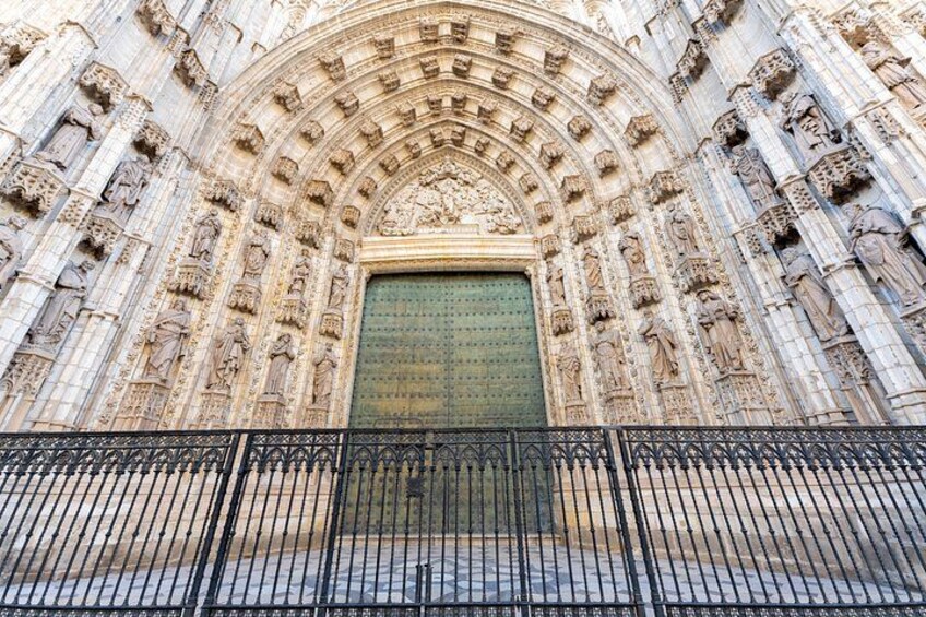 A Gothic cathedral facade with intricate stone carvings and a large green door. 3