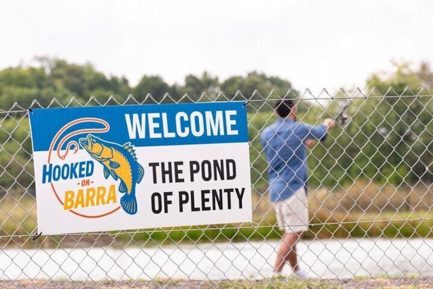 En person fisker bag et hegn med et skilt, der står 'Welcome to the Pond of Plenty'. 3