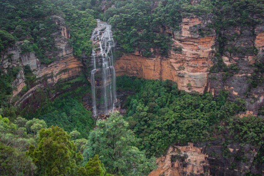 A waterfall cascading down a cliff surrounded by dense forest. 5