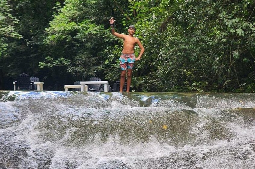 A person standing on a rock by a waterfall. 2