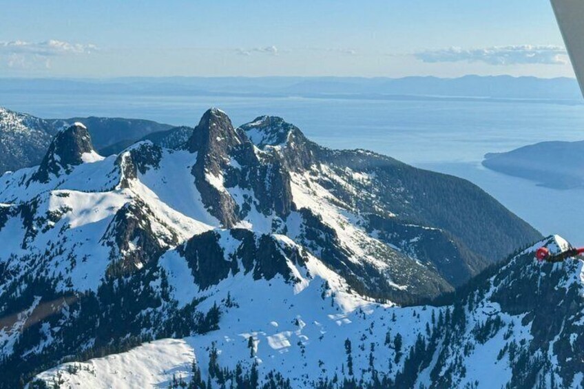 Snow-covered mountain peaks, a clear sky, and a distant body of water. 3