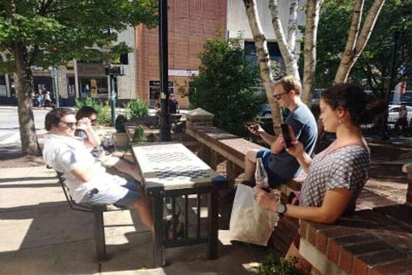 People sitting at outdoor tables, a brick wall, and a tree. 2
