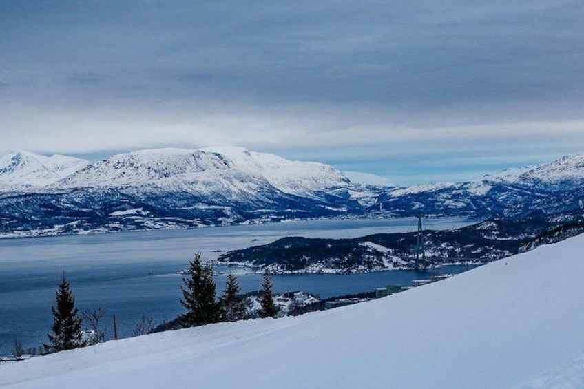A snow-covered mountain landscape with a lake and a bridge in the distance. 2