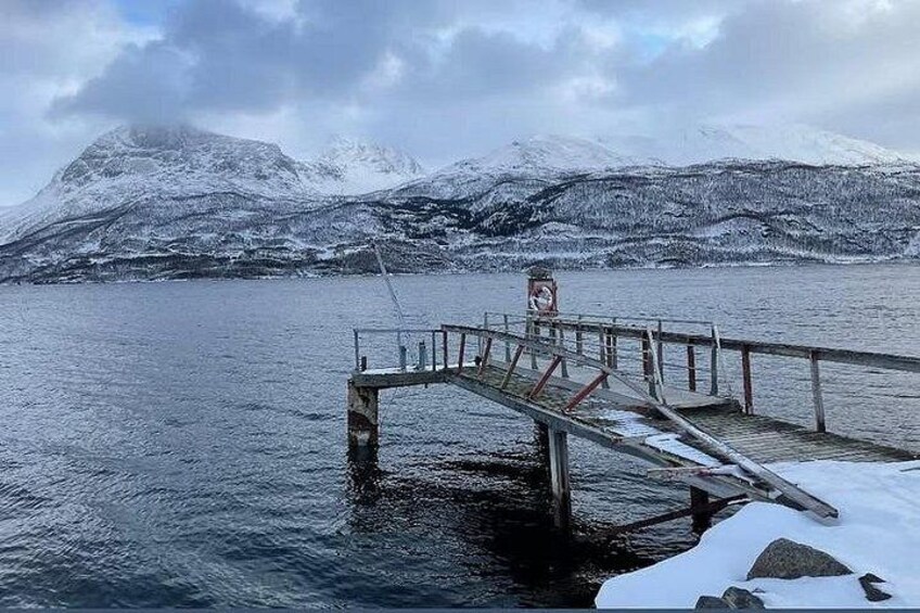 A snow-covered pier extending into a frozen lake with mountains in the background. 2