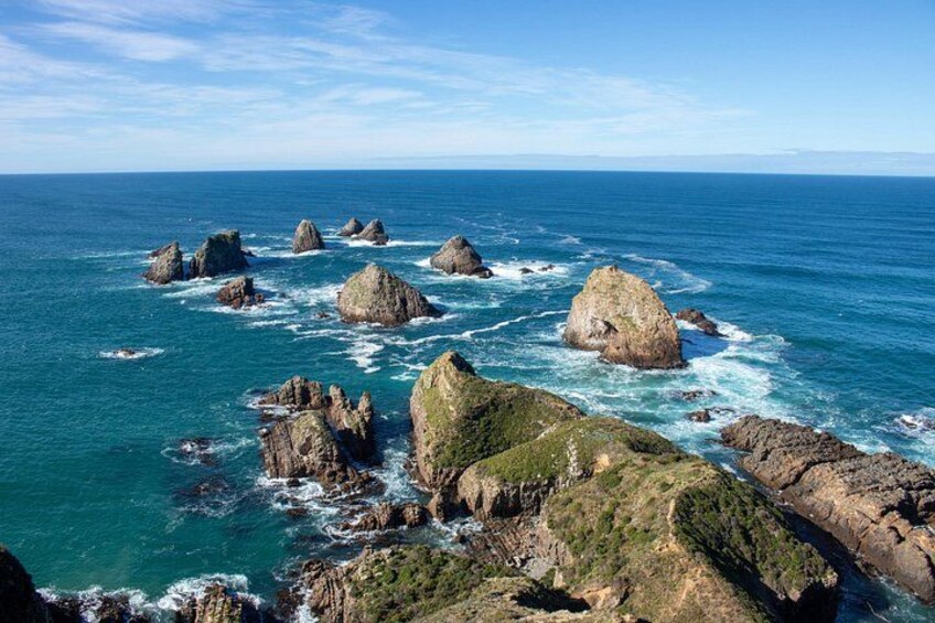 A coastal landscape with large rock formations and clear blue waters. 2