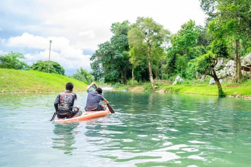 Two people paddling a small inflatable boat on a calm river surrounded by lush greenery. 4