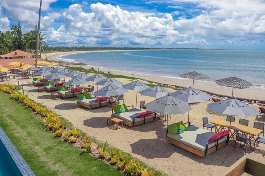 Un resort frente al mar con sillas de descanso y sombrillas, piscina y vistas al océano. 2