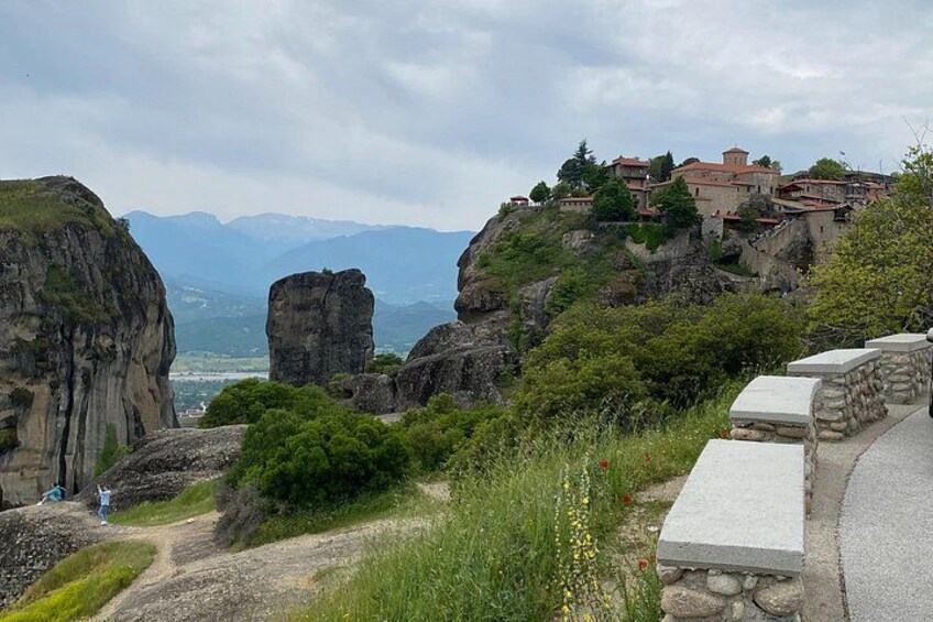A mountainous landscape with a stone pathway, rocky cliffs, and a village on a hill. 1