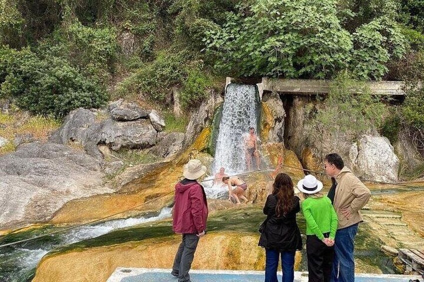 A group of people observing a waterfall in a natural setting. 2