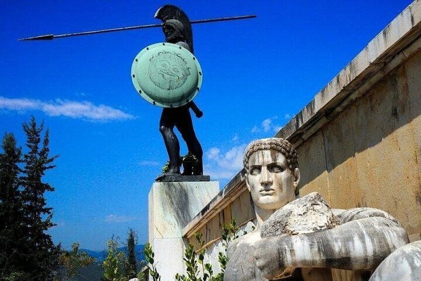 A statue of a warrior holding a shield and spear, with a classical bust in the foreground. 3
