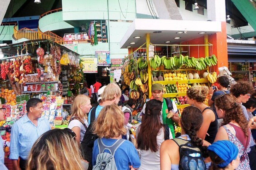 Een drukke openluchtmarkt met verschillende kraampjes die fruit en groenten verkopen. 5