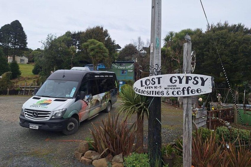 Een bestelwagen geparkeerd voor een bord waarop staat: 'LOST GYPSY CURIOSITIES & COFFEE'. 5