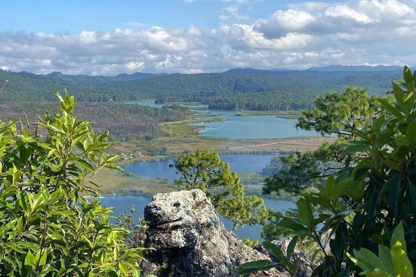 Un paisaje con un lago, colinas boscosas y una formación rocosa destacada. 5