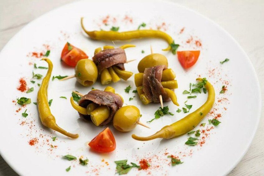 A plate of food with olives, tomatoes, and skewered meat. 2