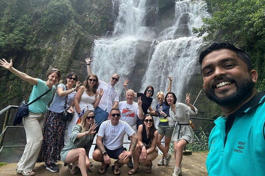 Eine Gruppe von Menschen posiert vor einem Wasserfall. 1
