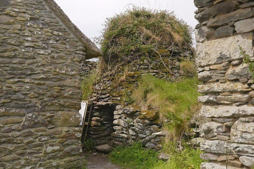 A stone building with a moss-covered roof and a narrow entrance. 5