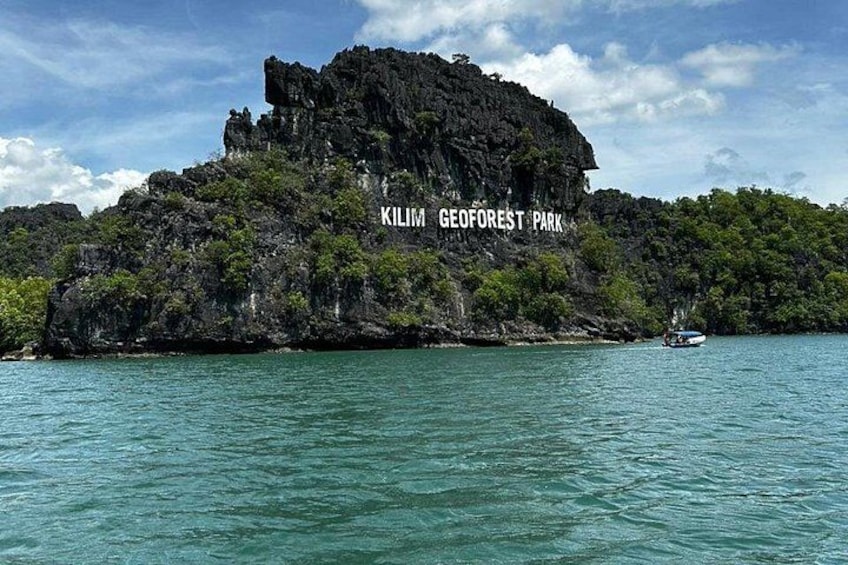 Une île rocheuse sur laquelle on peut lire l’inscription « PARC GÉOFORESTIER DE KILIM », entourée d’une eau turquoise. 1