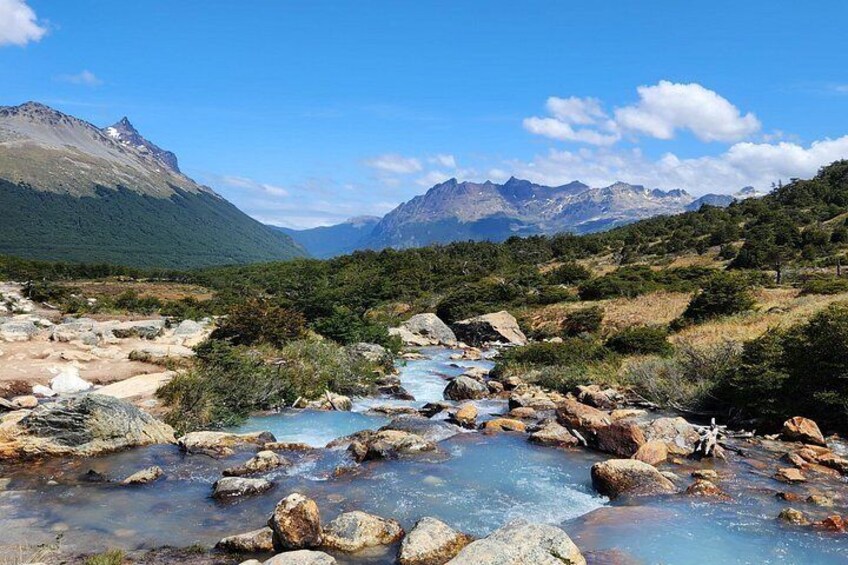 A mountainous landscape with a flowing river, rocky terrain, and distant mountains. 1