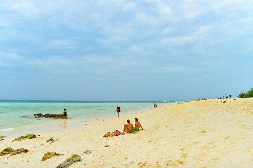 A beach with people walking and sitting on the sand, and the ocean in the background. 3