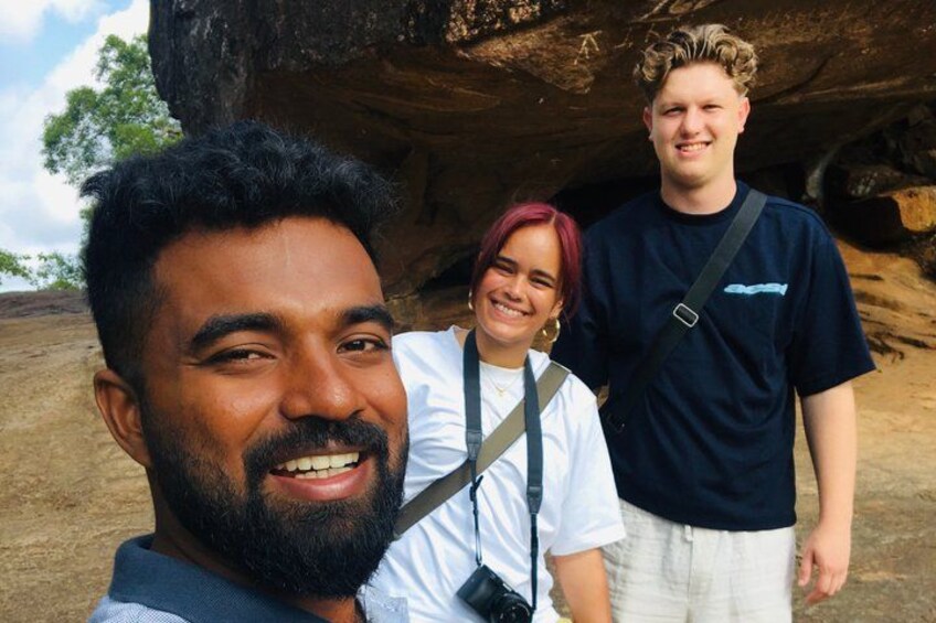 Trois personnes se tiennent devant une grande formation rocheuse. 4