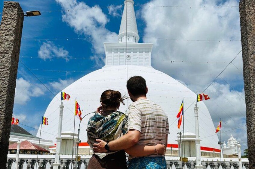 Un couple s’embrasse devant une grande structure en forme de dôme blanc, ornée de drapeaux. 2