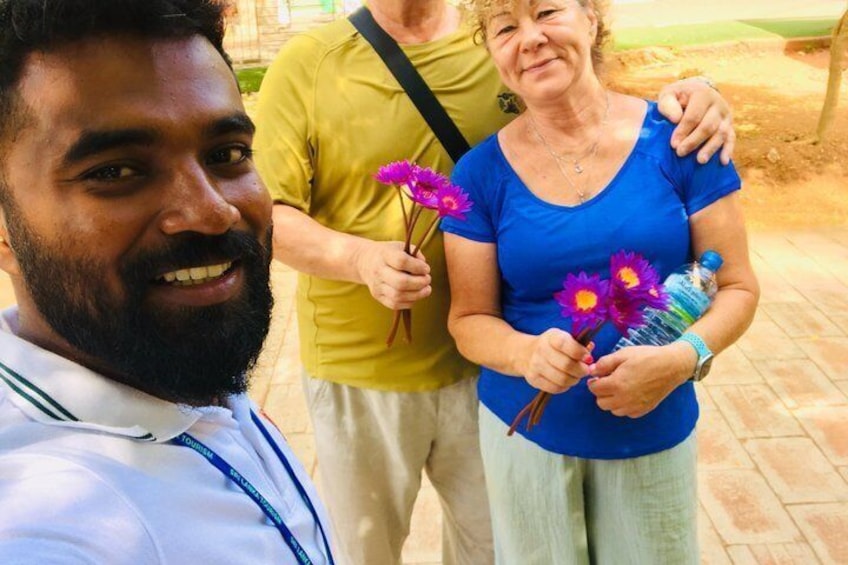 Una persona con una camisa blanca tomándose un selfie con otras dos personas sosteniendo flores. 3