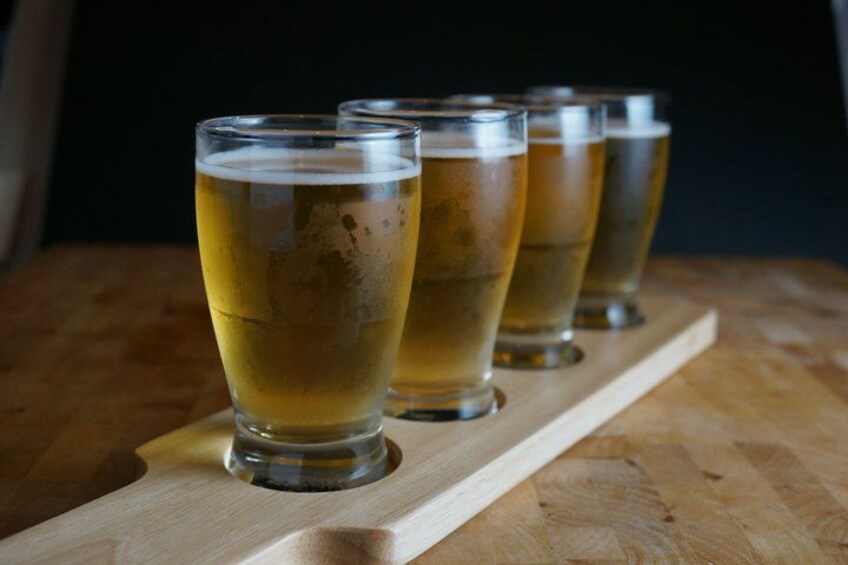 Four glasses of beer on a wooden tray. 1
