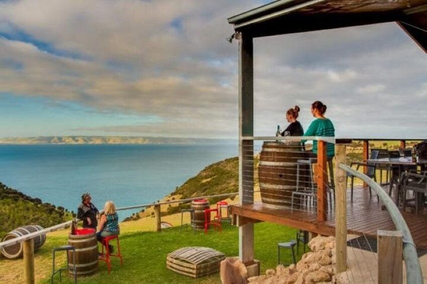 A coastal terrace with a view of the sea, a wooden deck, and outdoor seating. 1