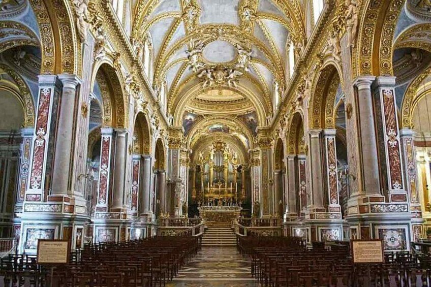 An ornate church interior with high ceilings, golden decorations, and rows of pews. 5