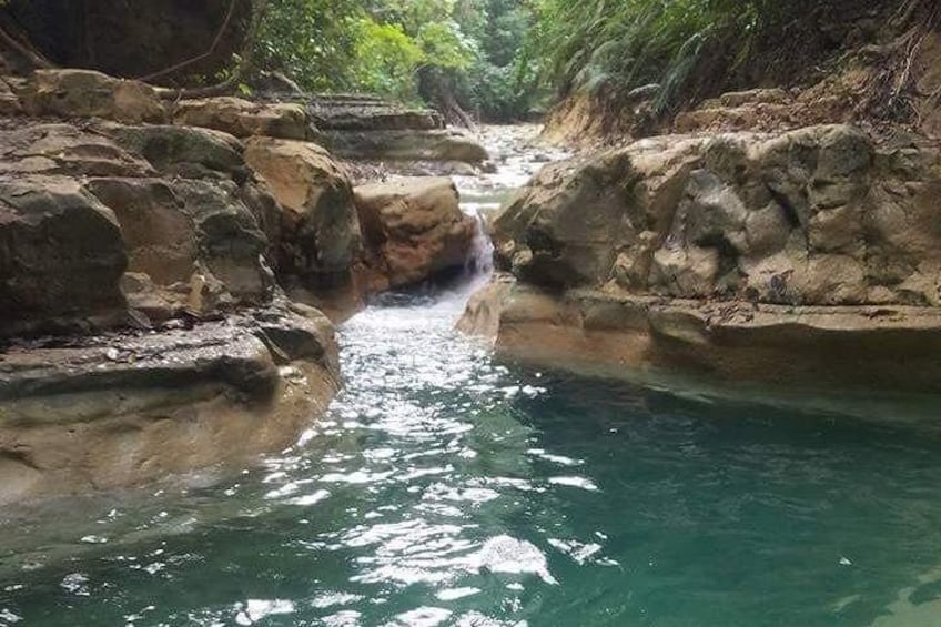 A natural water stream flowing through a rocky gorge with lush greenery. 5