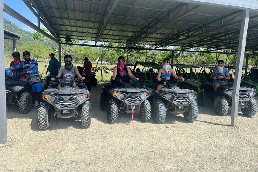 A group of people on ATVs parked under a shelter. 1