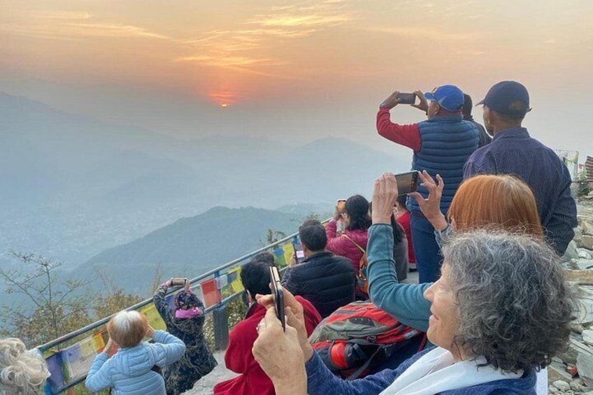 Personas en la cima de una montaña tomando fotos del atardecer. 3