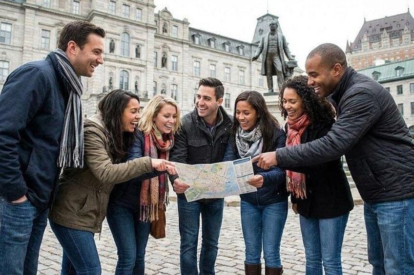 A group of people examining a map outdoors with historic buildings in the background. 1