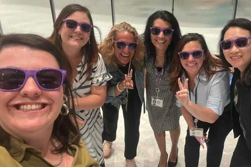 A group of people posing for a photo in an indoor setting with glass walls. 3