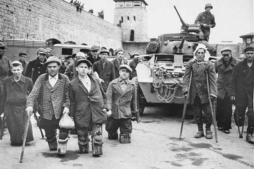 Een groep mannen in militaire uniformen loopt langs een tank en een gebouw. 2