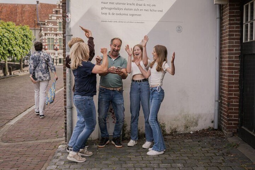 Un grupo de personas de pie señalando un muro con texto. 2