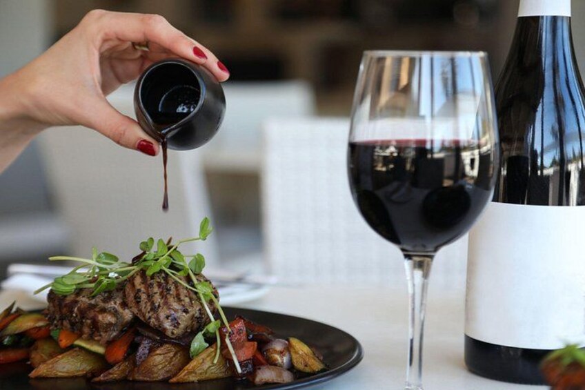 A hand pouring a dark liquid, possibly wine, into a glass. 2