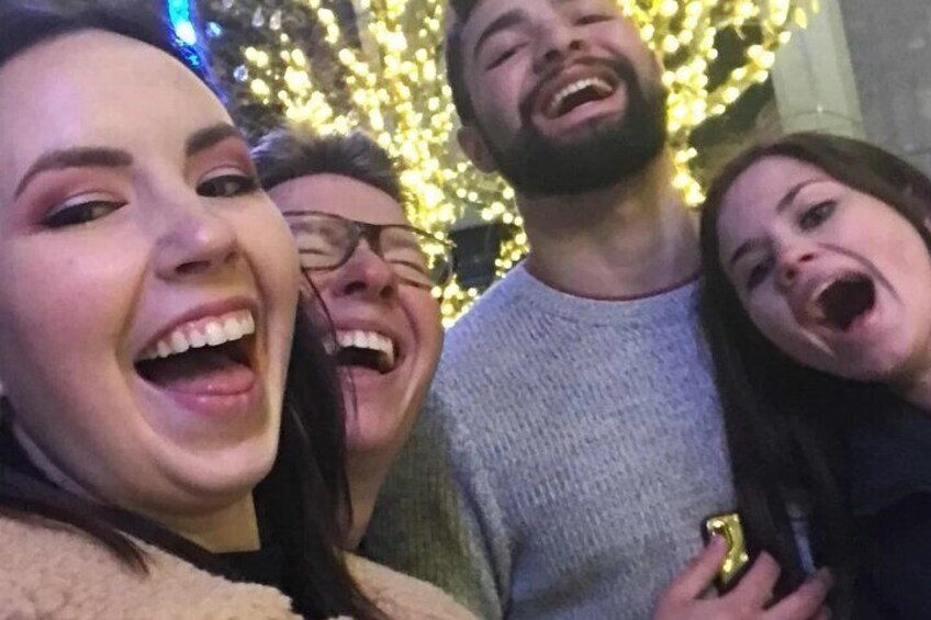 Een groep mensen in een feestelijke setting met verlichte lichtjes op de achtergrond. 2